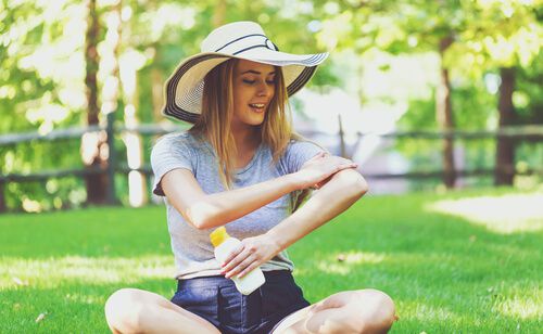 woman sitting on grass and applying sunscreen in Phoenix AZ