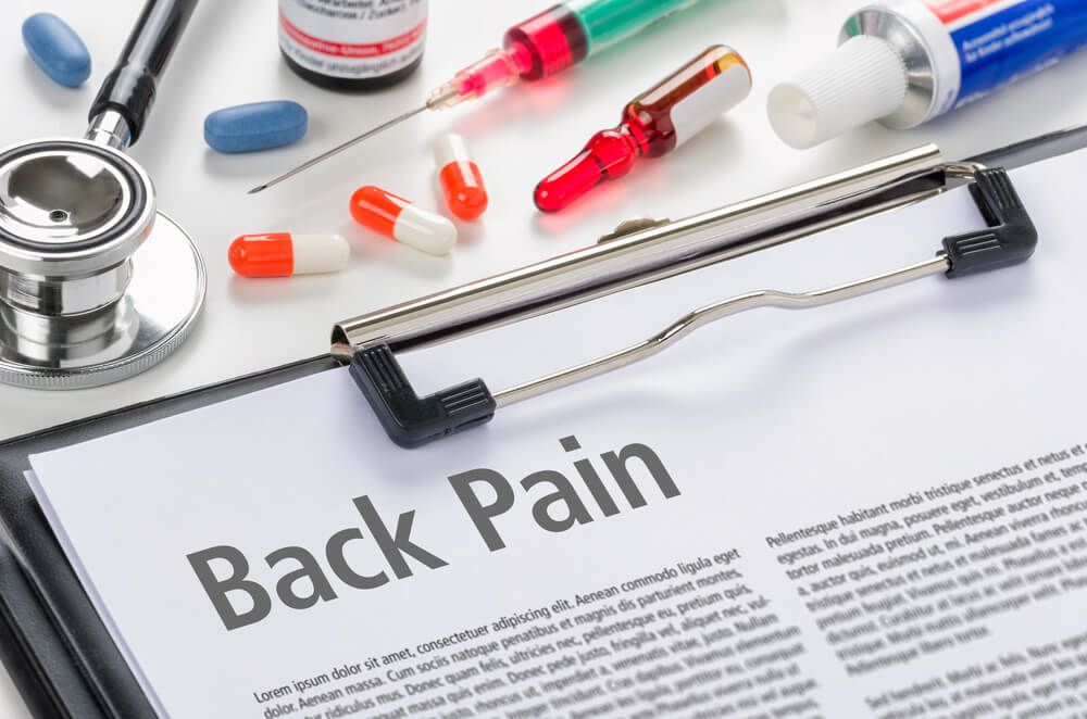 back pain medical diagnosis on clipboard surrounded by medications